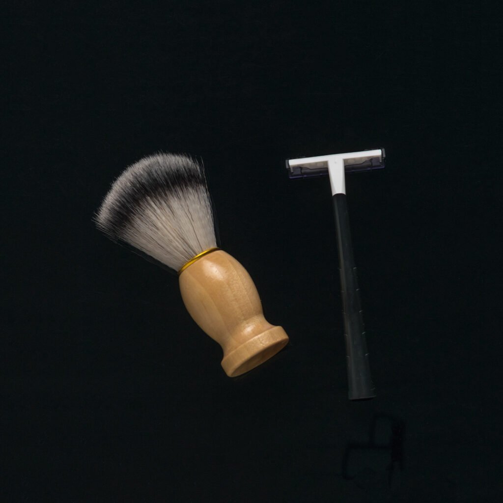 a shaving brush and a man's razor on a black background.